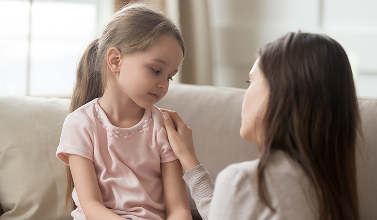 Loving mom talking to upset little child girl giving support